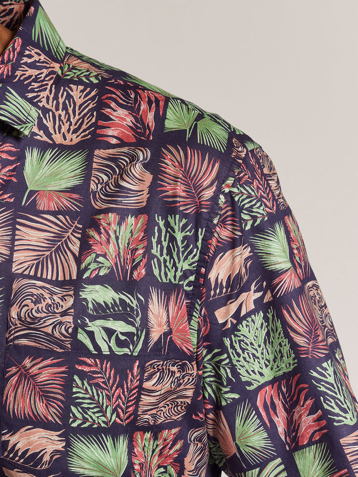 Red and mint green tropical leaf cotton lawn shirt with green, red, and beige tropical leaf print, front view.