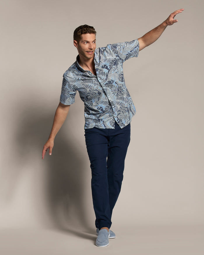 Man in blue floral short-sleeve shirt, navy pants, arms outstretched, front view .