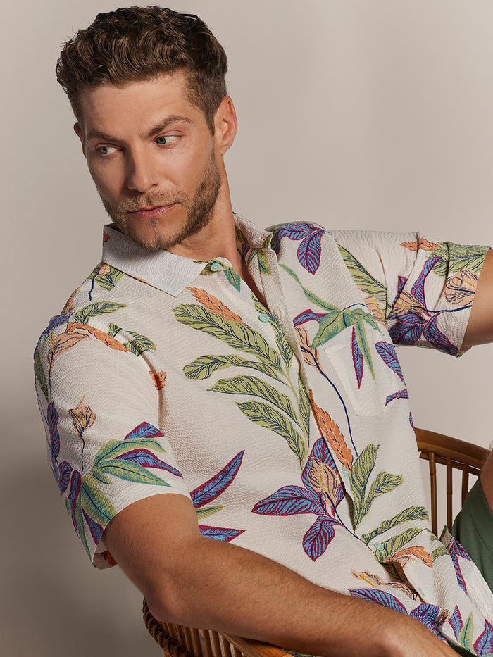 {{White calla lily-print short-sleeve shirt, seated front view on wooden chair}}{{/AltText}}.