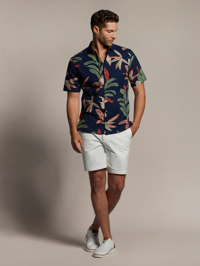 Man in navy Calla Lily-print short-sleeve shirt and white shorts, front view{{/AltText}}.