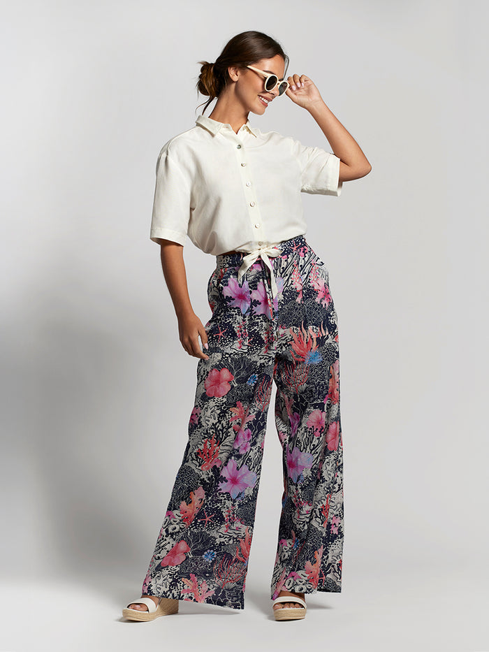 Coral and pink floral-print Evelyn pant with white shirt and sunglasses, front view.