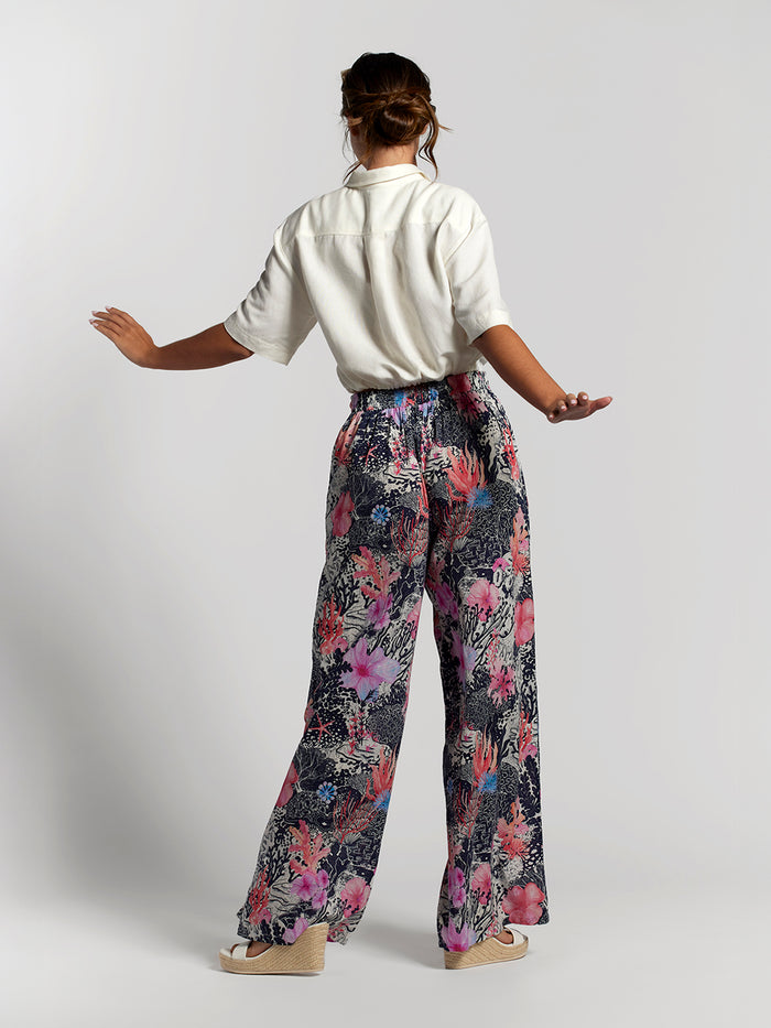 Coral floral-print Evelyn pant and white shirt, woman seen from the back with arms outstretched.