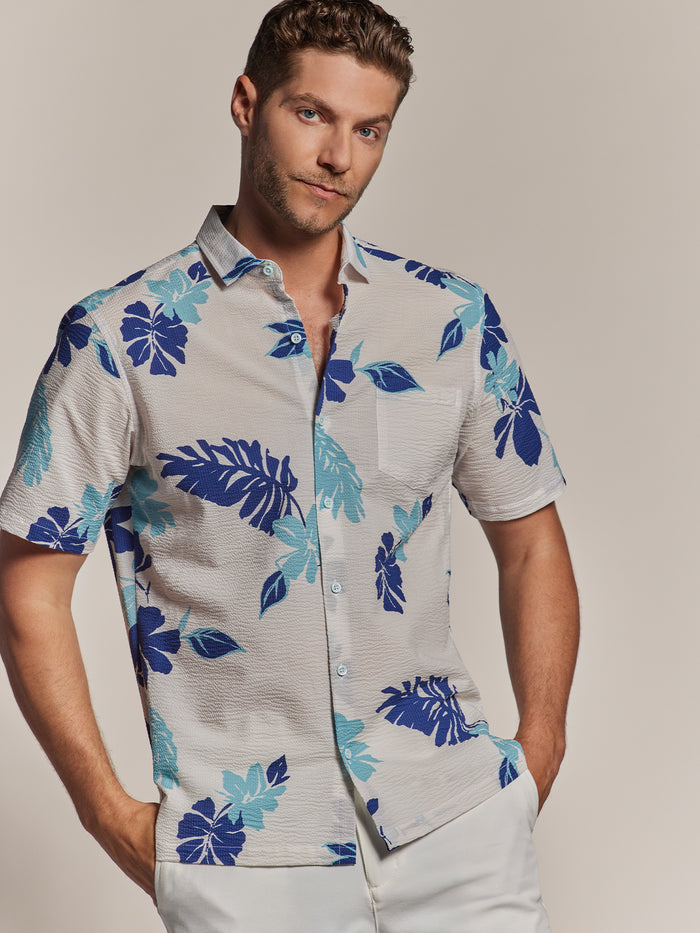 Blue and white floral-print cotton short-sleeve shirt, front view of a model on beige background.