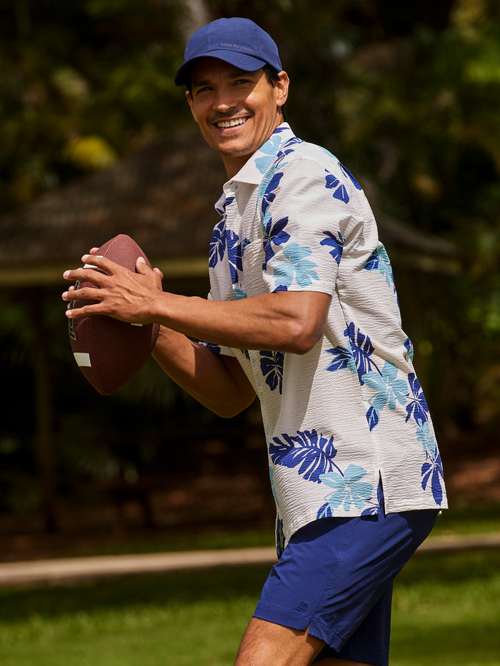 Blue floral-print short-sleeve shirt with blue shorts, outdoor three-quarter view .