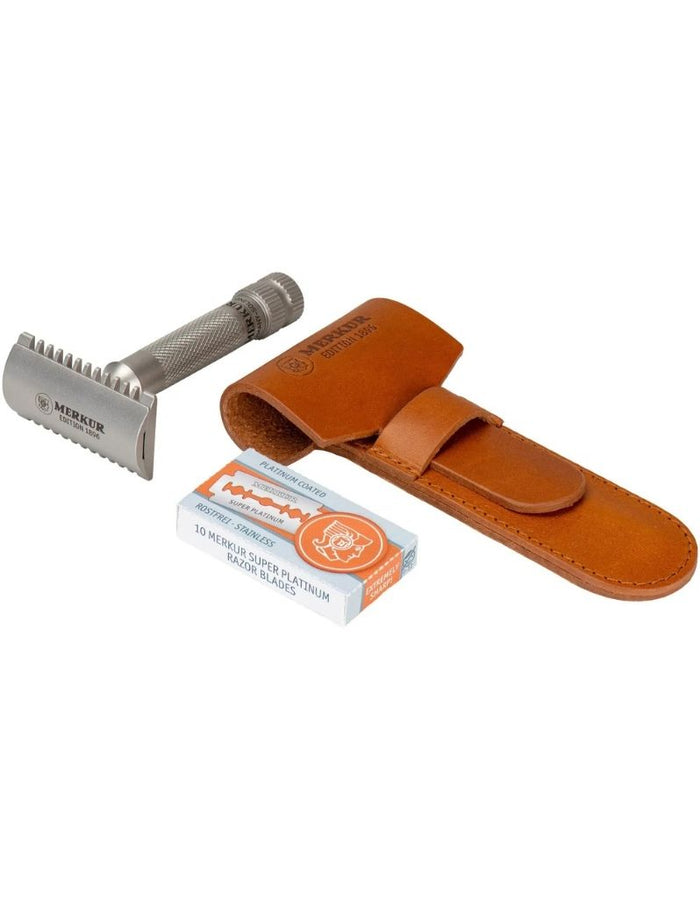 Close-up of Merkur stainless steel safety razor with textured grip, shown with leather protective case and packaging for grooming.