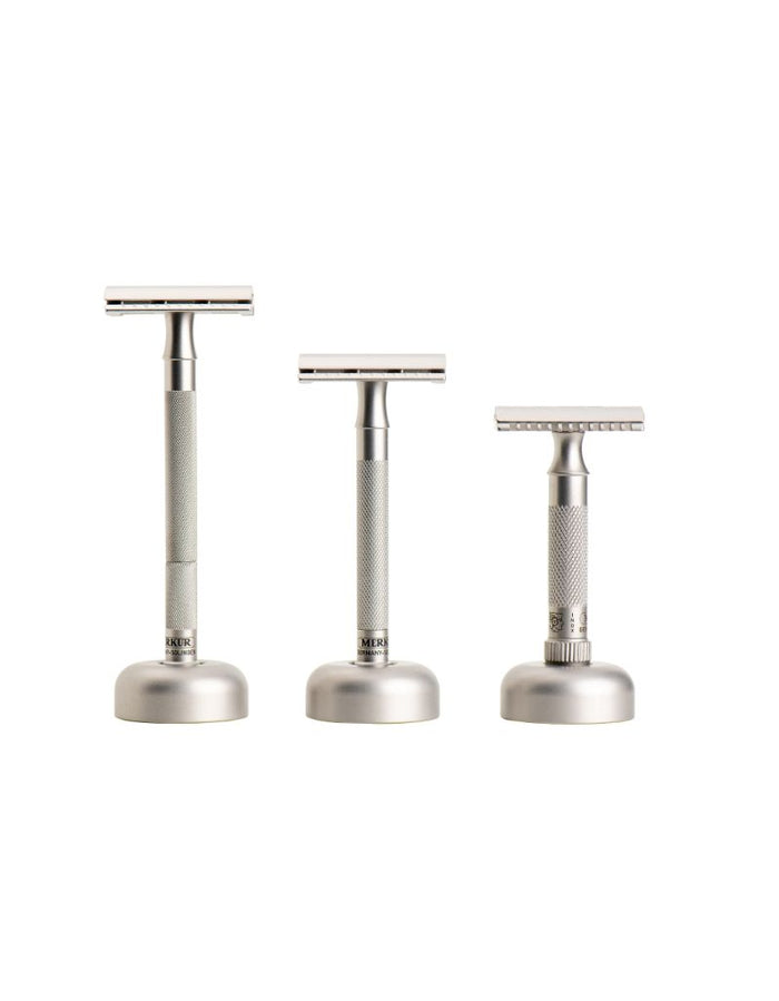 Three stainless steel safety razors in graduated sizes, arranged from largest to smallest on a solid white background.