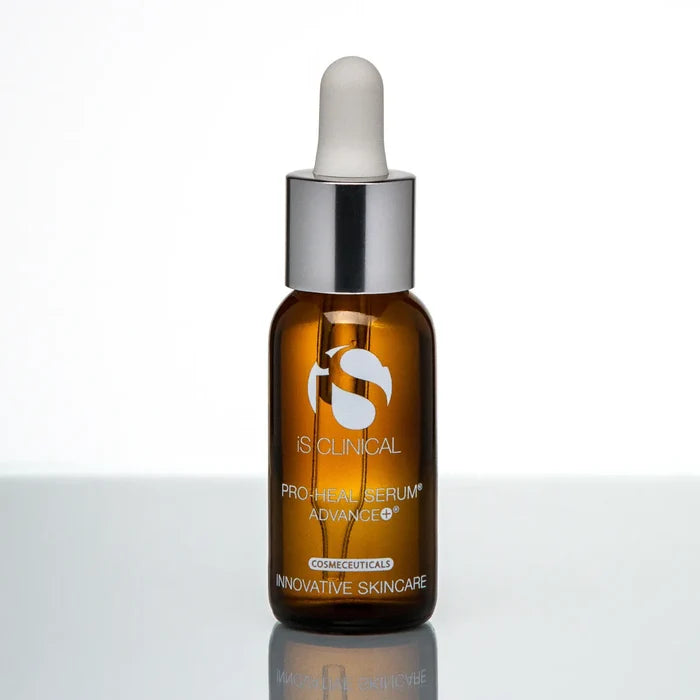 Amber glass dropper bottle of iS Clinical Pro-Heal Serum Advance+ with silver cap on reflective surface