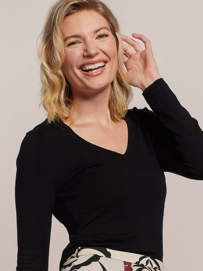 Woman wearing a black long-sleeve top with a neutral background