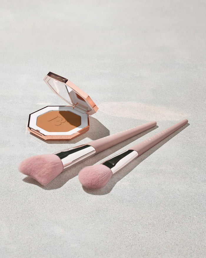 Sun Stalk'r Instant Warmth Bronzer with two light pink face brushes next to the open product