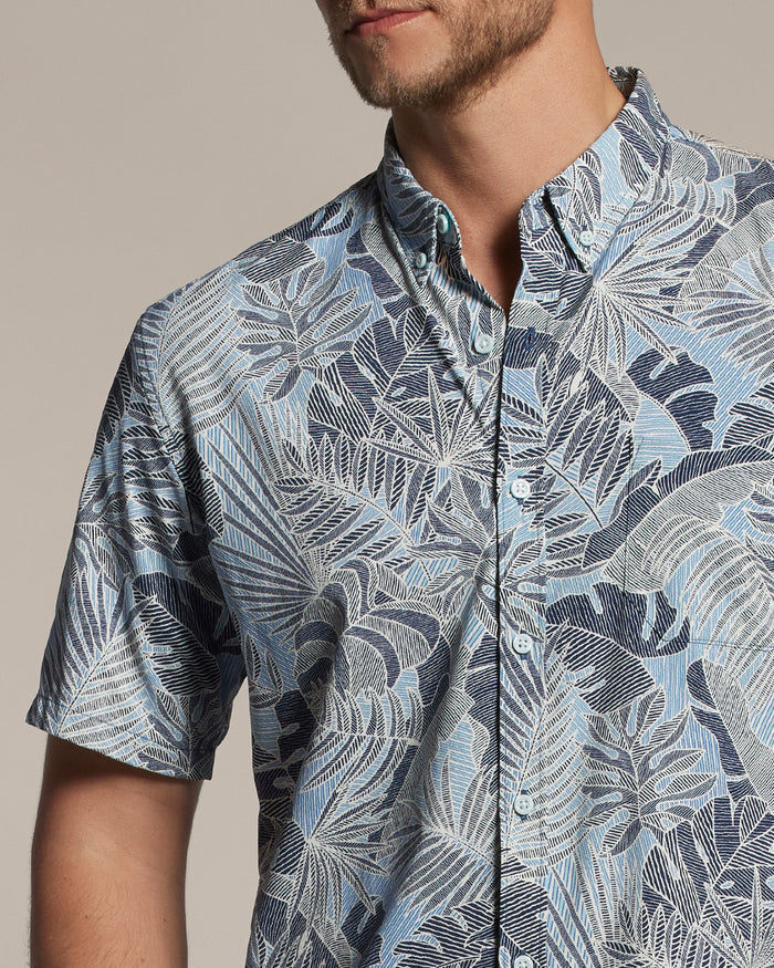 Blue and white tropical leaf-print short-sleeve shirt, model facing slightly left.