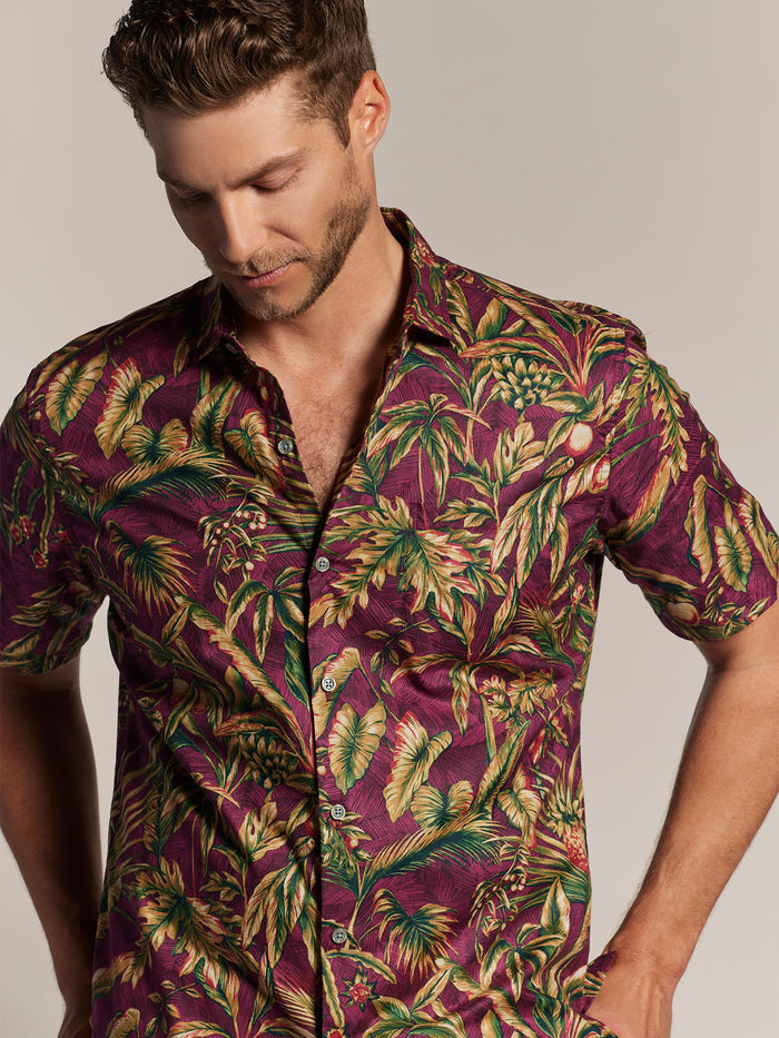 Maroon short-sleeve shirt with green/yellow tropical leaf print pattern tropical floral short-sleeve shirt, looking down, front view.